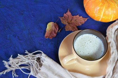 Kabak baharatlı latte veya fincan kahve, kuru yaprakları, koyu mavi masada hediyeler. Sonbahar veya kış sıcak içecek. Metin için alan, üst görünüm, kopyalama alanı