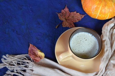 Kabak baharatlı latte veya fincan kahve, kuru yaprakları, koyu mavi masada hediyeler. Sonbahar veya kış sıcak içecek. Metin için alan, üst görünüm, kopyalama alanı