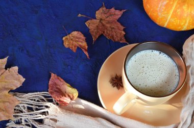 Kabak baharatlı latte veya fincan kahve, kuru yaprakları, koyu mavi masada hediyeler. Sonbahar veya kış sıcak içecek. Metin için alan, üst görünüm, kopyalama alanı