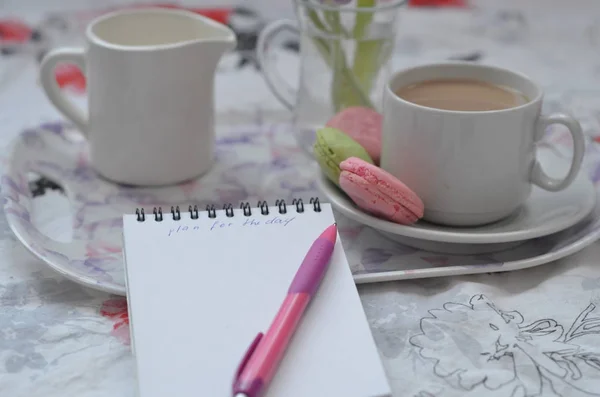 Bandeja con cuaderno de bocetos de papel, teléfono inteligente y flores de primavera sobre ropa de cama rosa. Relajarse, o trabajar, o escribir un diario o blog en la cama en casa . — Foto de Stock