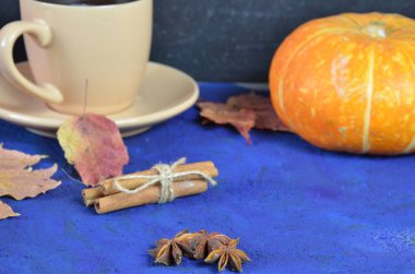 Kabak baharatlı latte veya fincan kahve, kuru yaprakları, koyu mavi masada hediyeler. Sonbahar veya kış sıcak içecek. Metin için alan, üst görünüm, kopyalama alanı