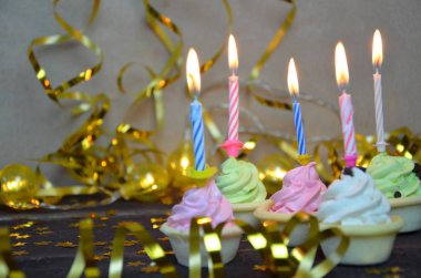 Cupcake renkli doğum günü mumları ile dekore edilmiştir. hediyeler, altın serpantin, yıldız, tatil kutlamak, parti.