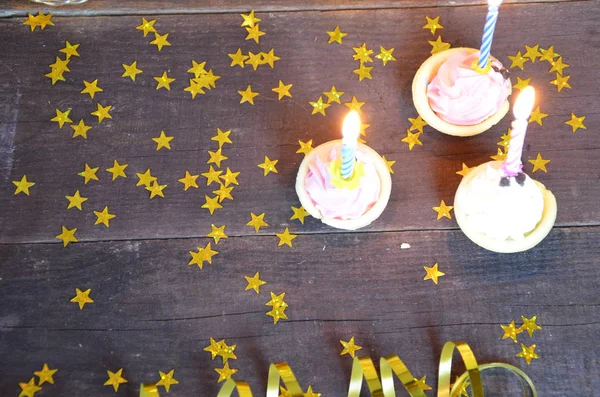 Cupcake versierd met kleurrijke verjaardag kaarsen. geschenken, gouden serpentine, sterren, vieren de vakantie, partij. — Stockfoto