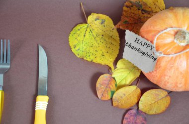 Şükran Günü. Balkabağı, sonbahar yapraklı ve elmalı balkabağı. Kahverengi arka planda sonbahar hasadı. Kutlama için Mutlu Şükran Günü Mektupları sehpaları. çatal ve bıçak