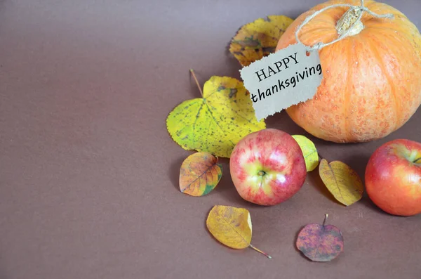 Den díkůvzdání. Dýně, dýně s podzimními listy a jablky. Podzimní sklizeň na hnědém pozadí. Šťastné Díkůvzdání, prostřený stůl na oslavu. vidlice a nůž — Stock fotografie