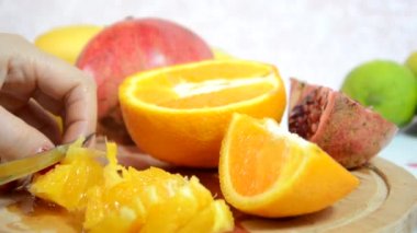Kız soyar ve kivi keser. Masada dilimlenmiş portakal, kivi ve elma var. Meyve salatası için taze kırmızı portakalı soyar ve keser. Diyet, az kalori, vejetaryenlik, doğal vitaminler..