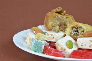 Lezzetli oryantal tatlılar baklava, koyu kahverengi arka planda bir tabakta Türk lezzeti.
