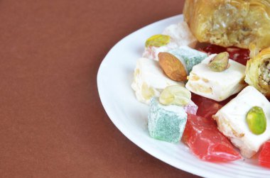 Lezzetli oryantal tatlılar baklava, koyu kahverengi arka planda bir tabakta Türk lezzeti.