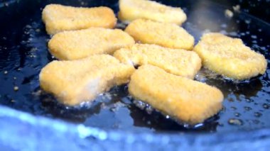 Kız tavada tereyağlı tavuk kızartması yapıyor. Lezzetli ev yapımı yemekler. Ya da fast food tavuk göğsü nuggetları.