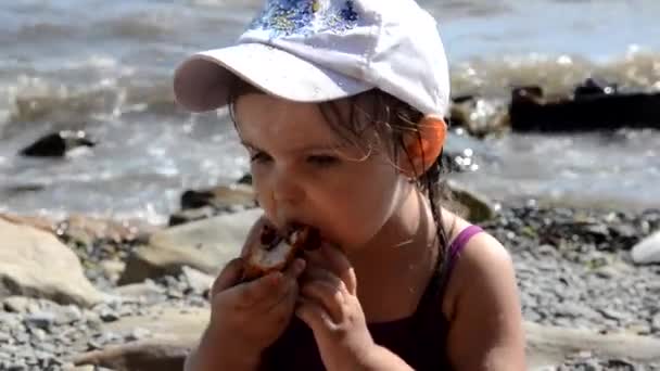 Menina feliz comer deliciosa torta doce com bagas fast food na praia. Lanche saudável e saboroso. belo mar no fundo, feriados, férias, infância — Vídeo de Stock