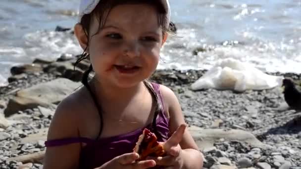 Happy dívka jíst lahodný sladký koláč s bobulemi rychlé občerstvení na pláži. Zdravá a chutná svačinka. krásné moře na pozadí, dovolená, dovolená, dětství — Stock video