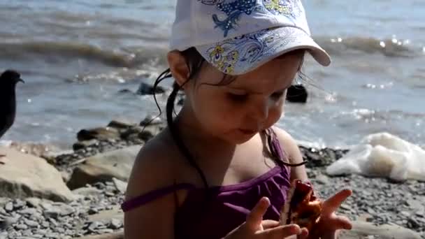 Счастливая девушка ест вкусный сладкий пирог с ягодами быстрого питания на пляже. Здоровые и вкусные закуски. красивое море на заднем плане, праздники, отпуск, детство — стоковое видео