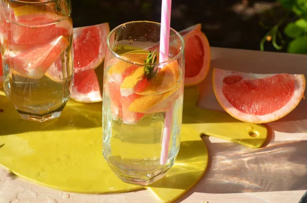 Taze meyve ve yeşil biberiyeli greyfurt suyu ile sağlıklı detoks smoothie pişiren bir kız. Yaşam tarzı detoks kavramı.