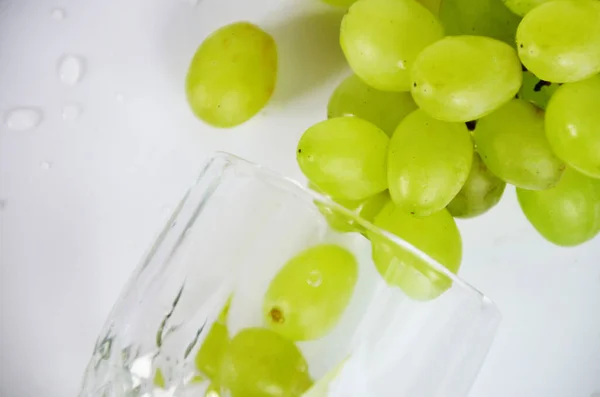 white grapes in a wine glass. White wine in a glass with fall grapes, white background, selective focus.