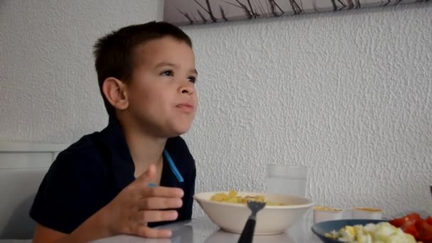 Słodki chłopiec je lunch, śniadanie lub kolację w domu widelcem, pije wodę. Zdrowe jedzenie w domu. Na tle białej ściany. dzieci jedzące zdrową żywność — Wideo stockowe