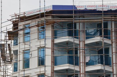İskeleli bina inşaatı, arka plan için pencere ofis binası.