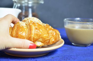 Bir tabak kruvasan ve sütlü kahve. Üst Manzara. Kruvasan susamla süslenmiş. Kahve çekirdeği ve süt sürahisinin bileşimini tamamla. Sağlıklı kahvaltı. Günaydın.