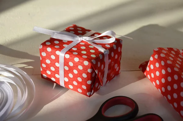 Christmas gift wrapping background, copy space. present box wrapped in kraft, top view. Winter holidays concept, flat lay. red manicure packing Christmas gift. scissors tape and gift wrapping paper.