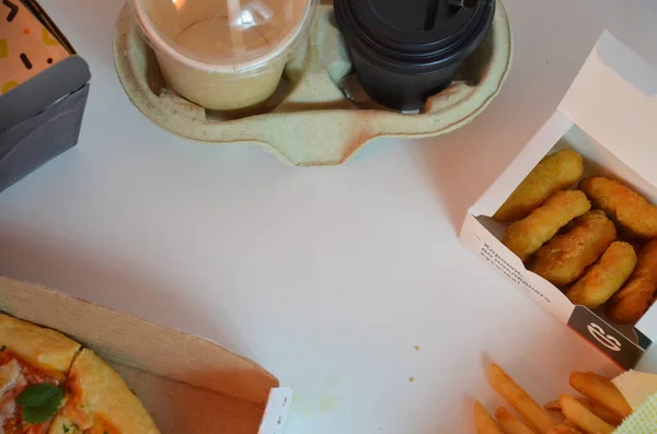 Çeşitli pizza kutuları, kağıt yemek kutuları, kabın içinde hazır kahve fincanları, yakın plan. Açık gri arka plan, ahşap yüzey. Yemek servisi. Patates kızartması, nugget.