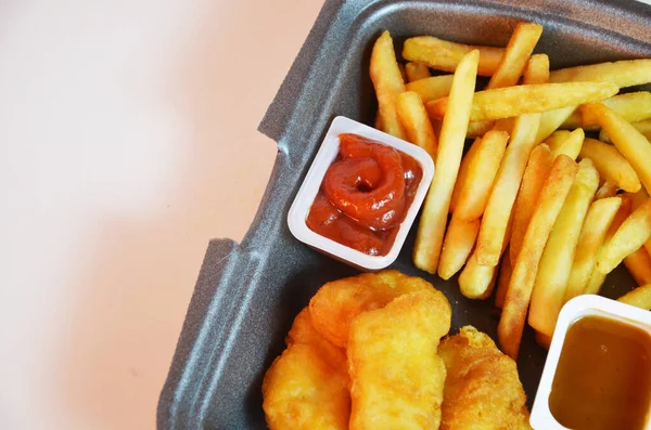 Yummy French fries, chicken Nuggets, sauce, paper bag, white background. Binge eating. food delivery.