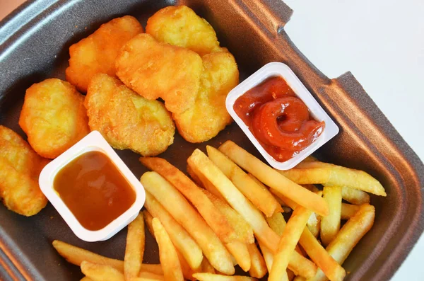 Lezzetli patates kızartması, tavuk nugget, sos, kese kağıdı, beyaz arka plan. Deli gibi yiyorum. Yemek servisi..