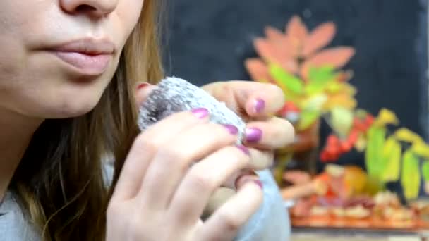 Een meisje eet een heerlijke chocoladetaart en drinkt in de herfst koffie in een café, tegen een achtergrond van gele en rode herfstbladeren. jong mooi vrouw eten een dessert — Stockvideo