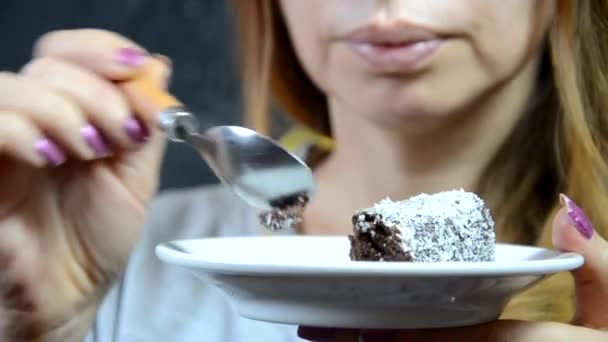 Ein Mädchen isst im Herbst vor dem Hintergrund gelb-roter Herbstblätter einen leckeren Schokoladenkuchen und trinkt Kaffee in einem Café. junge schöne Frau isst ein Dessert — Stockvideo