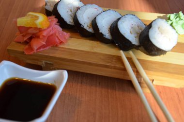 Somon balığı ve havyar ruloları, bir restoranda, yemek çubuklarıyla birlikte bir masada servis edilen suşi rulolarında servis edilir. Soya soslu, kızıl ve portakallı..
