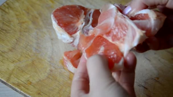 女孩在家里厨房的切菜板上剥下柚子。柑橘类节食。健康食品。用刀把柚子切成两半 — 图库视频影像