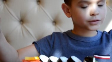 Genç bir çocuk Çin bambu çubuklarıyla suşi rulosunu alıp soya sosunun içine düşürüyor ve bir parça pembe zencefil alıyor. Yeşil wasabi zencefil ve sosun yanında beyaz porselen tabakta Japon mutfağı.