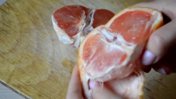 Dívka oloupe grapefruit na prkně v kuchyni doma. citrusy. dietu. zdravé jídlo. Řízením grapefruitu na dvě poloviny nožem — Stock video