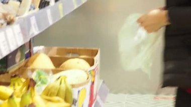 Güzel genç bir kadın yiyecek, meyve, elma, muz, domates, markette, süpermarkette portakal alıyor. Kız ürünleri, sebzeleri, meyveleri dükkandan seçiyor..