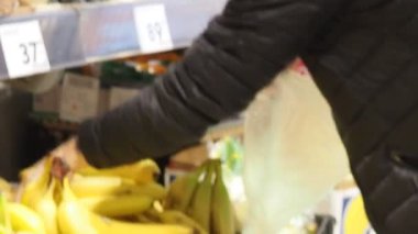 Güzel genç bir kadın yiyecek, meyve, elma, muz, domates, markette, süpermarkette portakal alıyor. Kız ürünleri, sebzeleri, meyveleri dükkandan seçiyor..