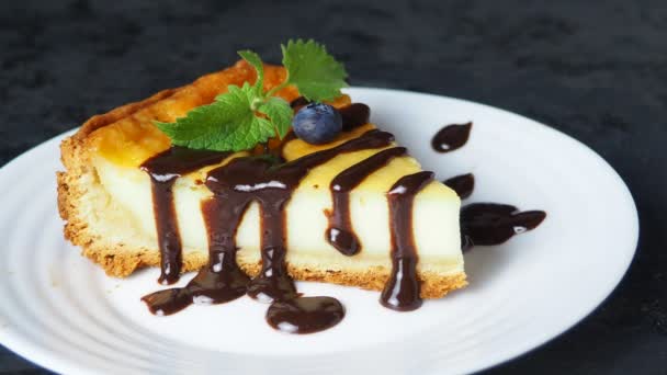 Lezzetli bir cheesecake dilimi ve siyah bir masada meyve.. — Stok video