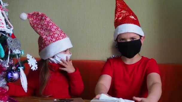 Mała dziewczynka i chłopiec w masce, Wirus Bożego Narodzenia i koncepcja pandemii, brat i siostra rozpakować prezenty, koncepcja nowego roku, rodzina — Wideo stockowe