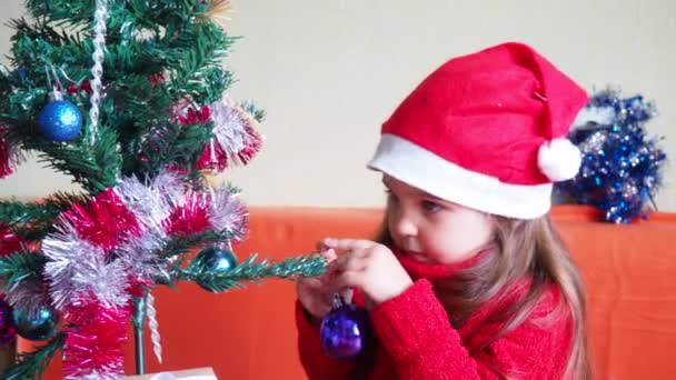 Gelukkig klein meisje versieren kerstboom met mooie ornamenten en kerstballen genieten van feestelijke decoraties thuis op rustige winteravond 4k beeldmateriaal — Stockvideo