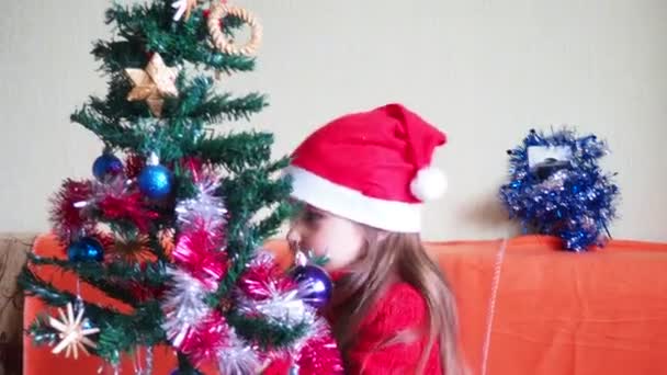 Feliz niña decorando árbol de Navidad con hermosos adornos y adornos disfrutando de decoraciones festivas en casa en calma noche de invierno 4k metraje — Vídeo de stock