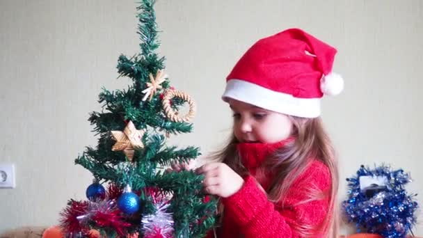 Menina feliz decorando árvore de Natal com belos ornamentos e bugigangas desfrutando de decorações festivas em casa na calma noite de inverno 4k imagens — Vídeo de Stock