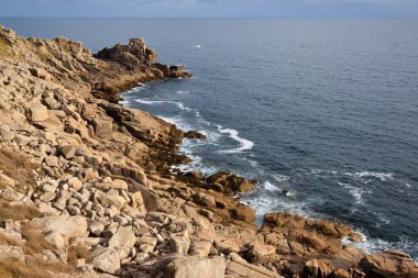 Kayalık sahil şeridi mavi deniz ve gökyüzü ile küçük tekne uzakta. Kopya için alan