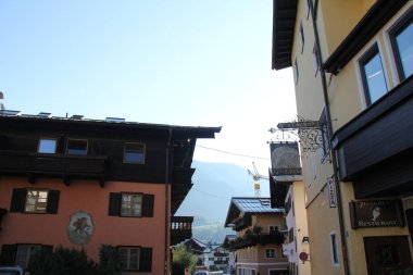 KITZBUEHEL, AUSTRIA - 8 Ağustos 2025: Tarihi şehir merkezinin dar bir caddesinde geleneksel renkli evler ve restoran tabelaları. Yüksek kalite fotoğraf