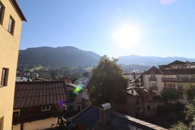 KITZBUEHEL, AUSTRIA - AUGUST 8, 2025: Scenic view over rooftops towards the Alps with the sun shining above the mountains. High quality photo