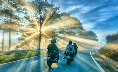 Da Lat, Vietnam - 13 Mayıs 2018: motosiklet, çam ormanları sisli güzel yolda parlayan güneş ışınlarının ile yolda sürüş bu Da Lat Yaylası, Vietnam güzel yola çıktı.