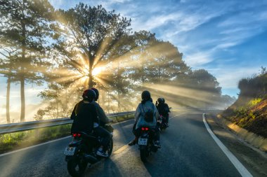 Da Lat, Vietnam - 13 Mayıs 2018: motosiklet, çam ormanları sisli güzel yolda parlayan güneş ışınlarının ile yolda sürüş bu Da Lat Yaylası, Vietnam güzel yola çıktı.