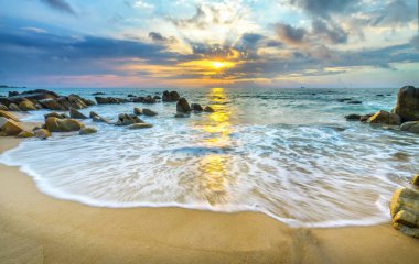 Şafak ile sahilde birçok güzel şekiller oluşturmak için beyaz kum çizgiler dalgalar ipek gibi güzel plajları üzerinde birçok kayalar vardır,