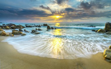 Şafak ile sahilde birçok güzel şekiller oluşturmak için beyaz kum çizgiler dalgalar ipek gibi güzel plajları üzerinde birçok kayalar vardır,