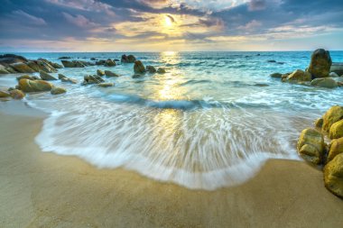 Şafak ile sahilde birçok güzel şekiller oluşturmak için beyaz kum çizgiler dalgalar ipek gibi güzel plajları üzerinde birçok kayalar vardır,