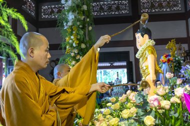 Ho Chi Minh City, Vietnam - May 29, 2018: Group of Vietnamese buddhists monks bath Buddha statue purify body and spirit in Buddha birthday celebration at pagoda in Ho Chi Minh City, Vietnam clipart