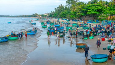 Phan Thiet, Vietnam - 30 Eylül 2018: Sepet balık satış içinde balık pazarı oturum denizler sahne kişi toplandı yorucu kürek balıkçılar balık kıyıya balıkçı köyü Phan Thiet, Vietnam getirdi