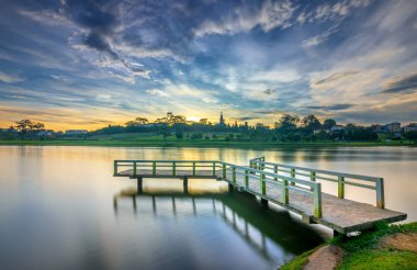 Sunrise dramatik gökyüzü ile göle bakan küçük köprüde yeni gün Vietnam turist şehir ağırlamaktadır.