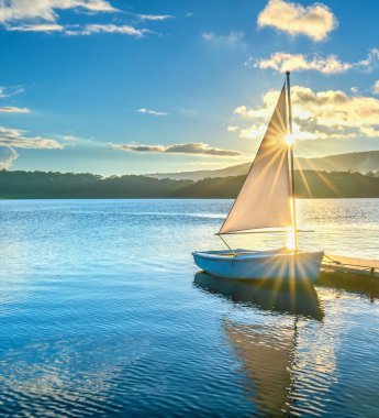 Gökyüzünden güzel günbatımında güneş yıldız ile yalnız Yelkenli parlar ve göl yüzeyine onları izlerken sakin ve huzurlu